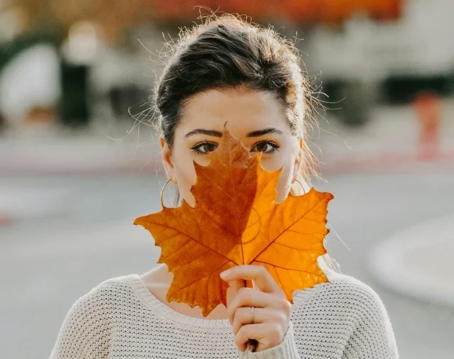 mujer detrás de hoja de árbol