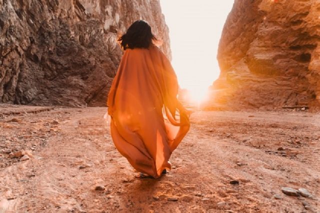 mujer vestido naranja caminando montañas
