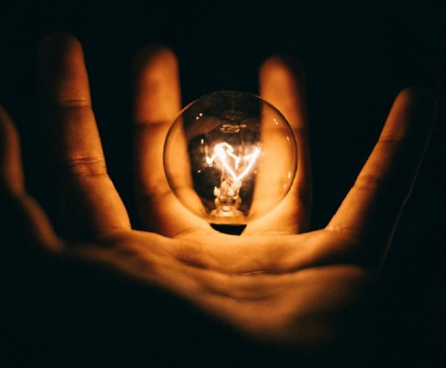 foco luz amarilla entre manos