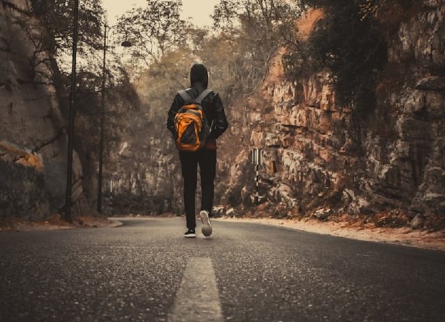hombre caminando en carretera de regreso