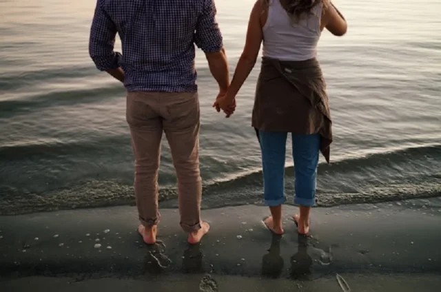 pareja camina descalza en la arena